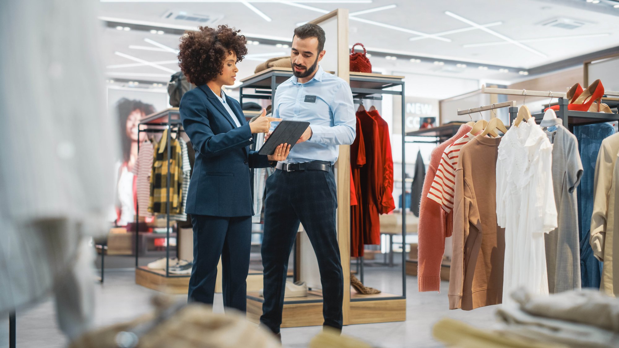 Man and woman discussing in retail shop with tablet device in hand
