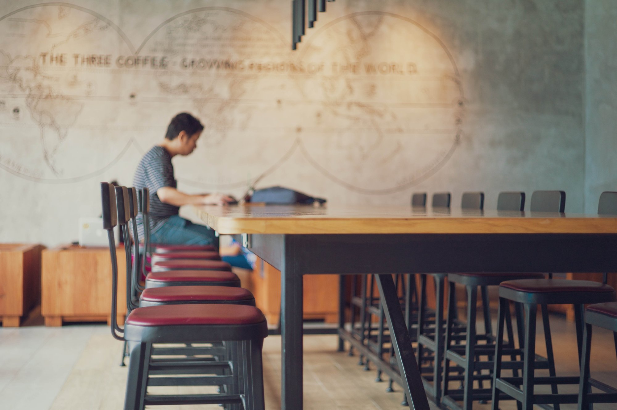 Man sitting on a stool in the distance using a laptop in a cafe