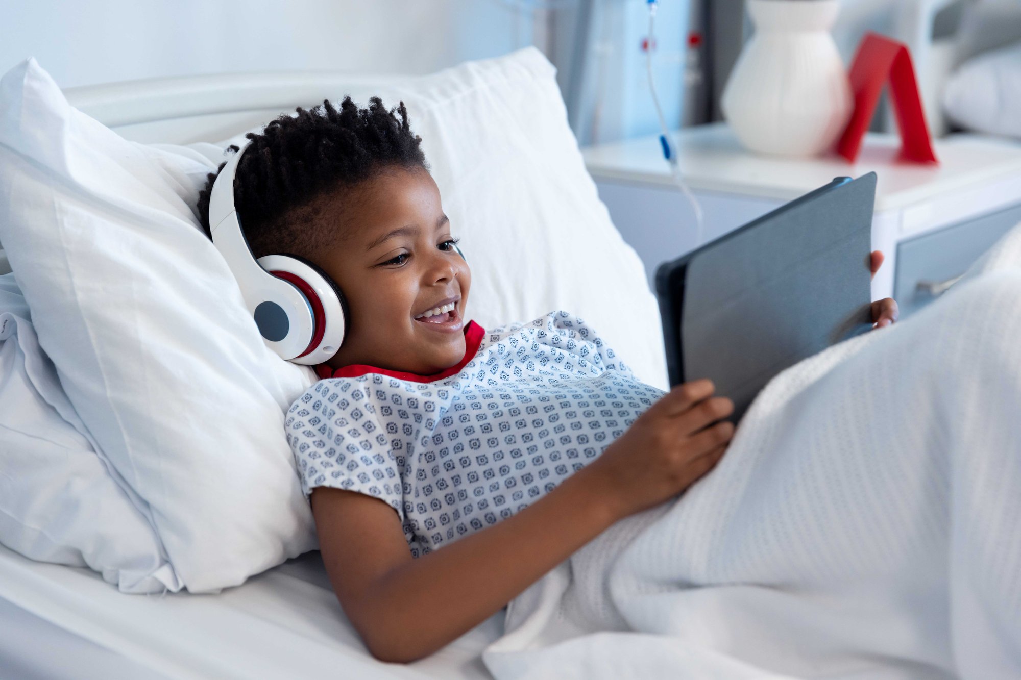 Child patient in hospital bed using tablet