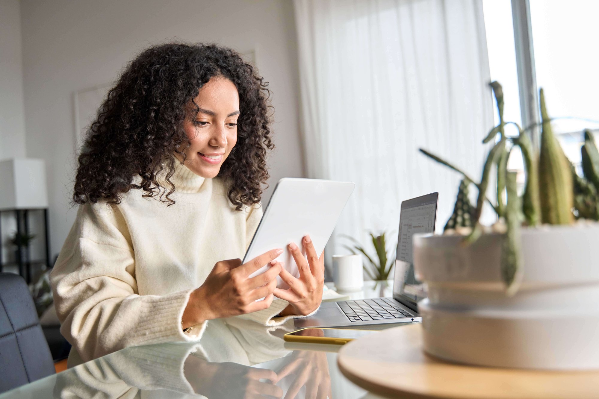 Woman looking at tablet device sat by a table