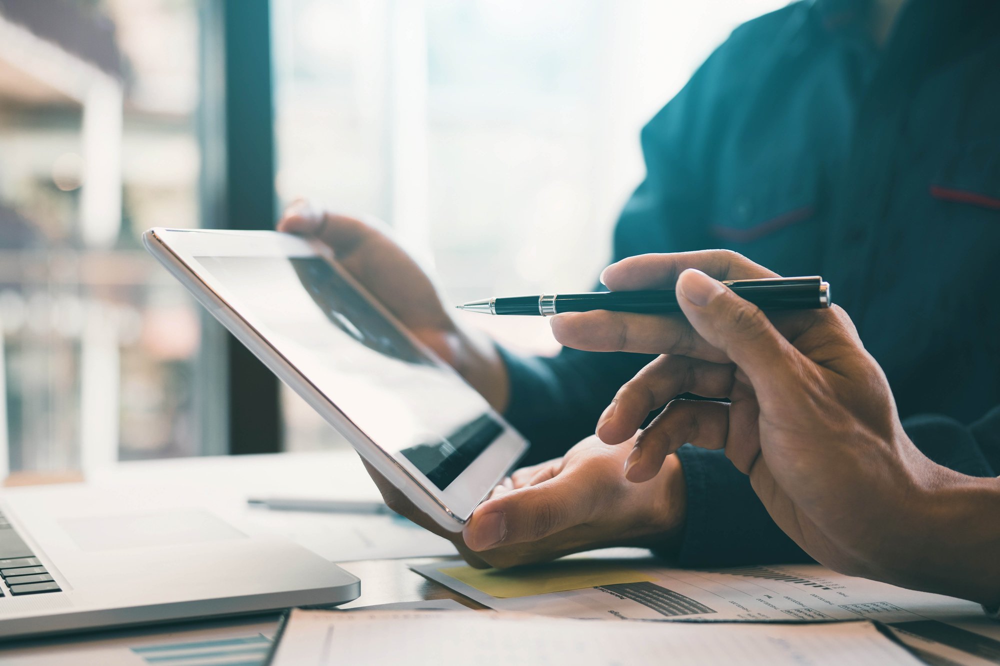 Close up of tablet device with hand holding a pen pointing at screen