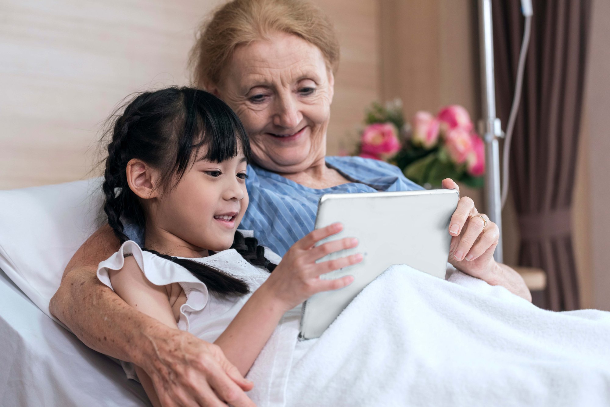 Woman and child in hospital bed looking at tablet device together
