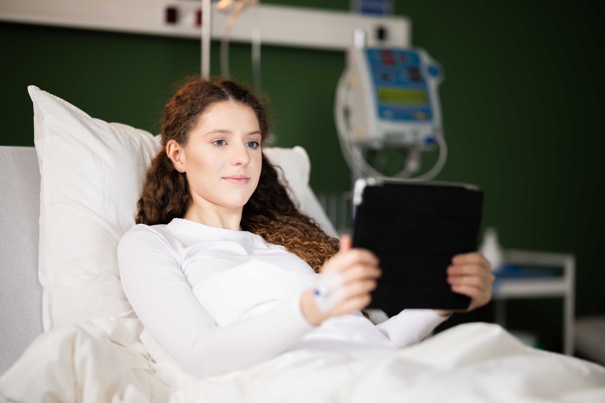 Patient in hospital bed watching tablet device